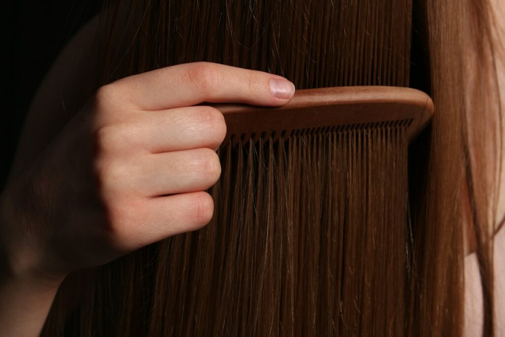 A hand combing long brown hair